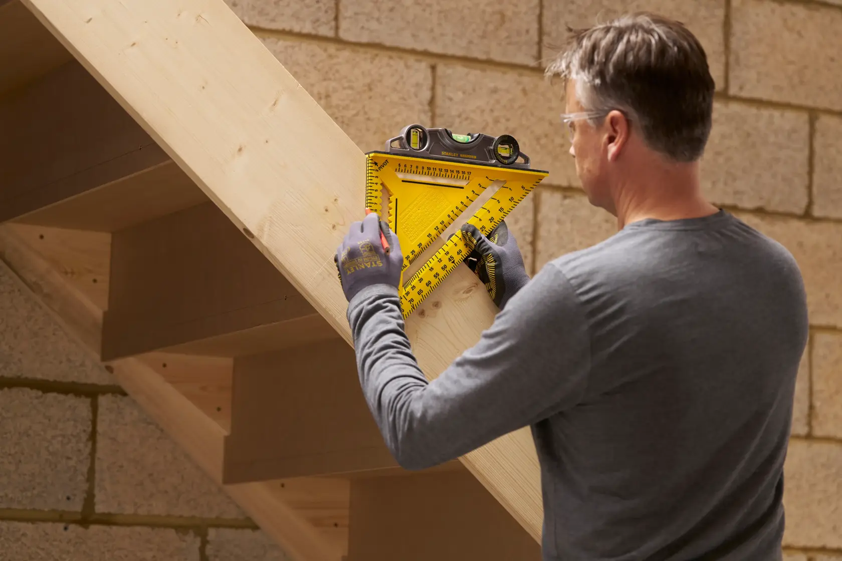 STANLEY STHT46013-0 yellow layout square with built-in level used on wooden stairs construction.