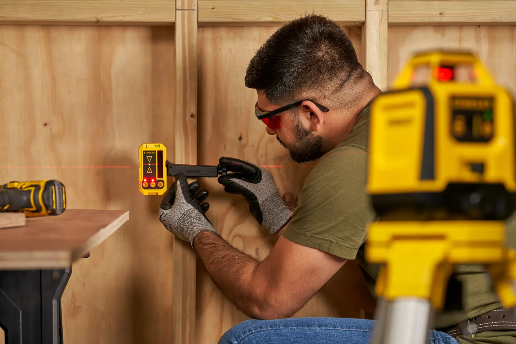 STANLEY STHT77616-0 laser detector in use for wall leveling, shown with gloves and laser level equipment.
