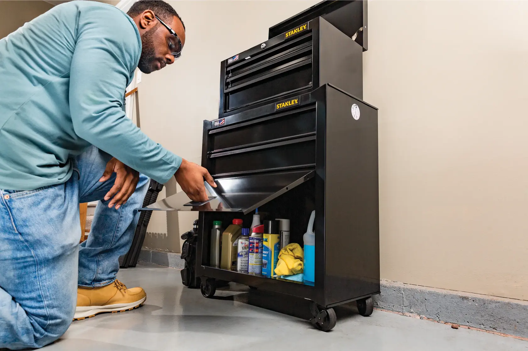 Photo of STANLEY STST22656BK black rolling tool chest with open drawers, showing storage of bottles and cloths.