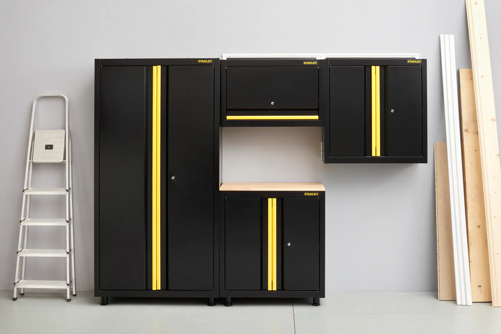 STANLEY STST97598-1 black and yellow garage storage cabinets set, front angle, with ladder and wood planks.