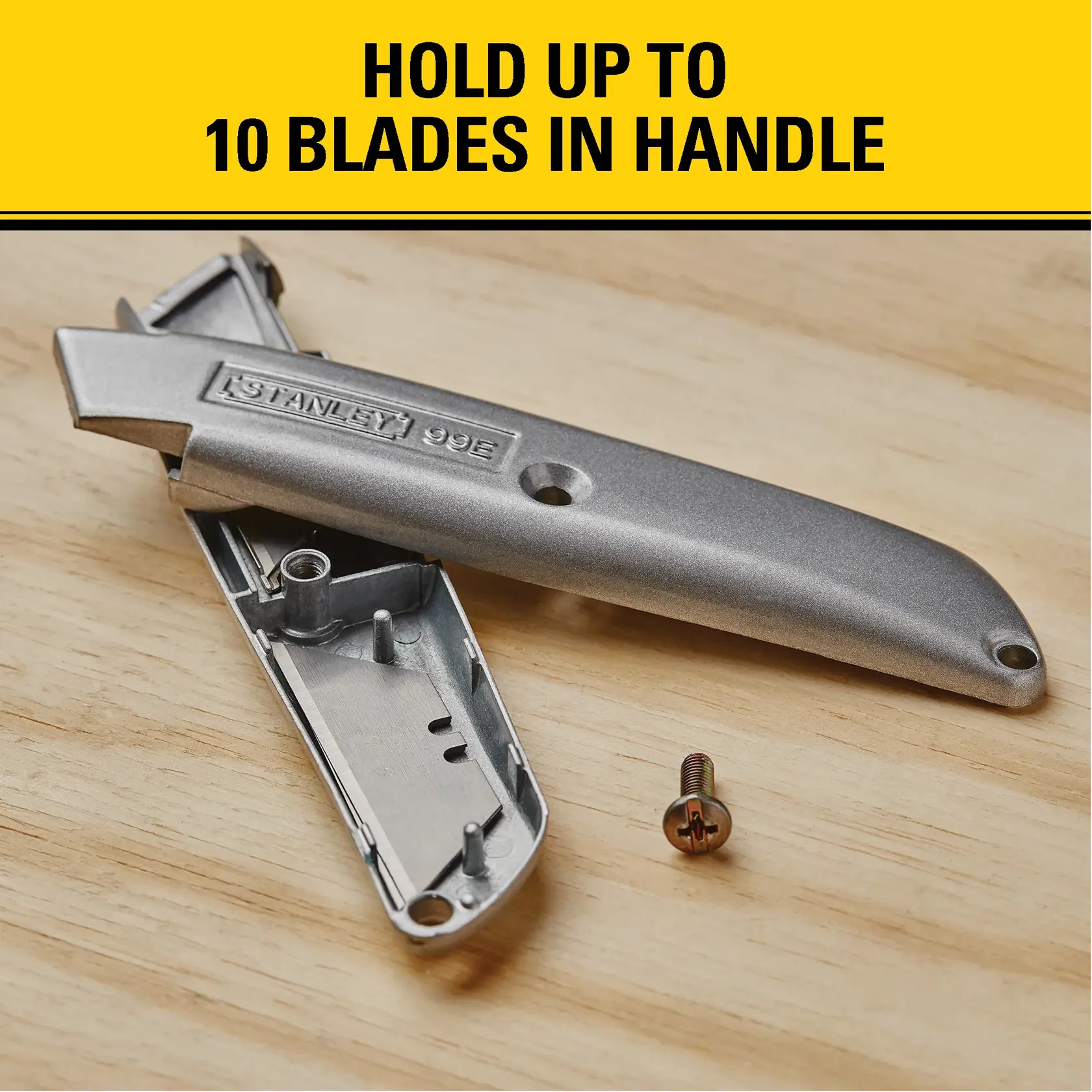 A metallic Stanley 99E utility knife with its handle open, displaying internal storage space for up to 10 blades and a screw, placed on a wooden surface. The image includes text stating 'HOLD UP TO 10 BLADES IN HANDLE.'
