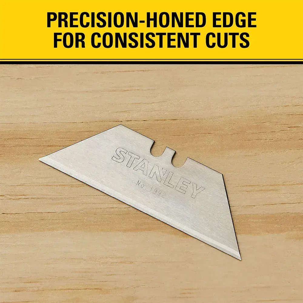 A Stanley utility knife blade (model 11-921) displayed on a wooden surface, with the text 'Precision-honed edge for consistent cuts' above.