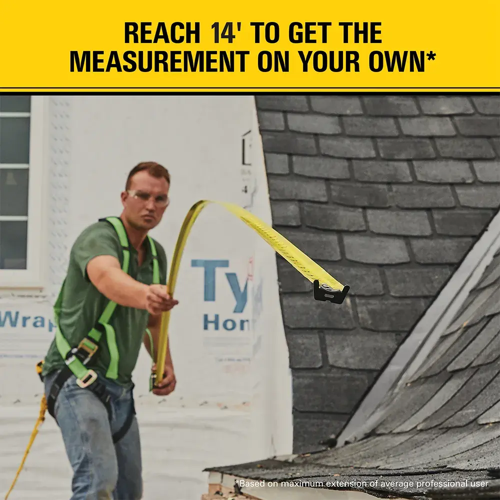 A construction worker using a STANLEY tape measure, extended to 14 feet, to take a measurement on a building site. There is a yellow banner with the text 'REACH 14' TO GET THE MEASUREMENT ON YOUR OWN*' at the top.