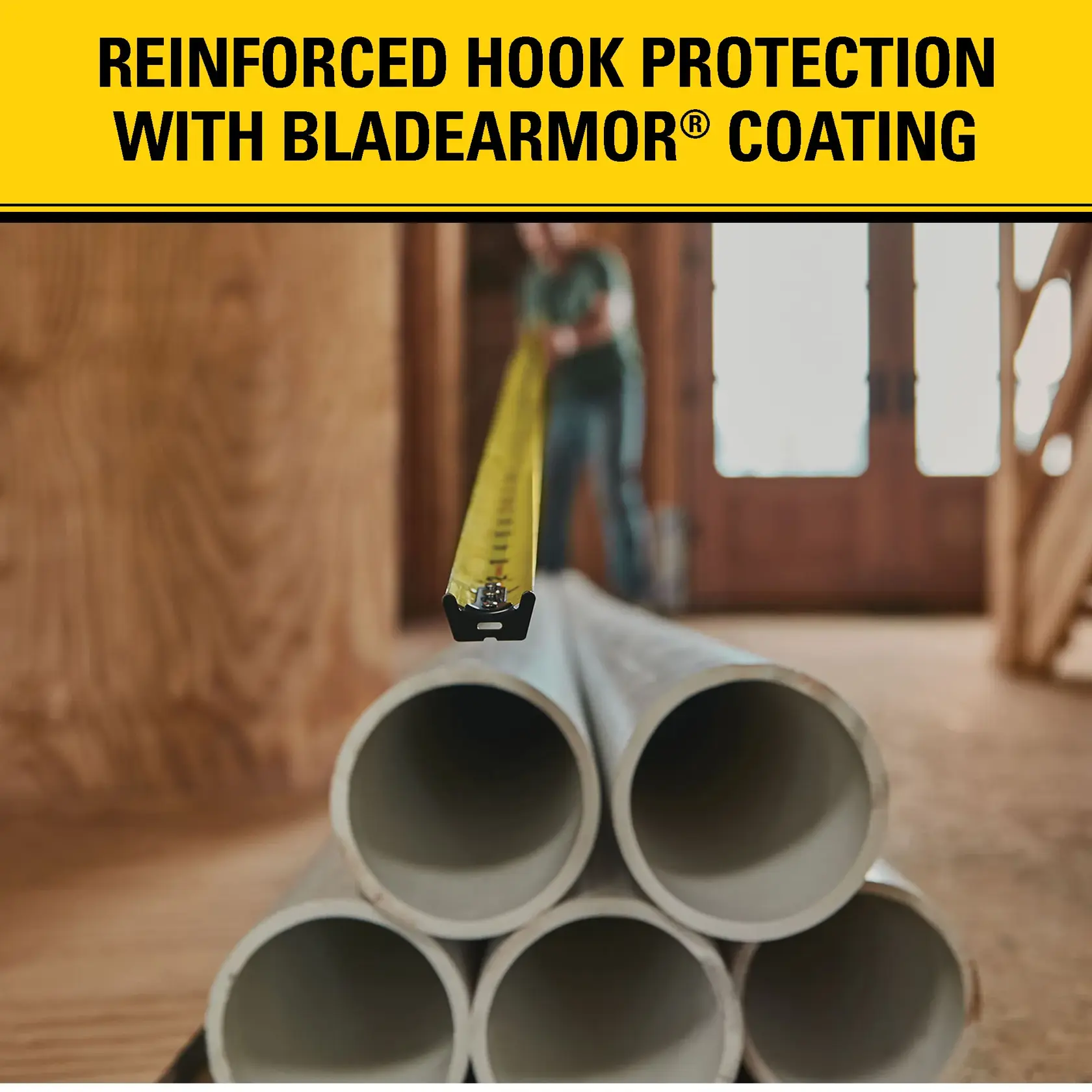 A close-up view of a tape measure extended across several stacked pipes in a construction setting. The tape measure features reinforced hook protection with BladeArmor coating, as described in the text above the image.