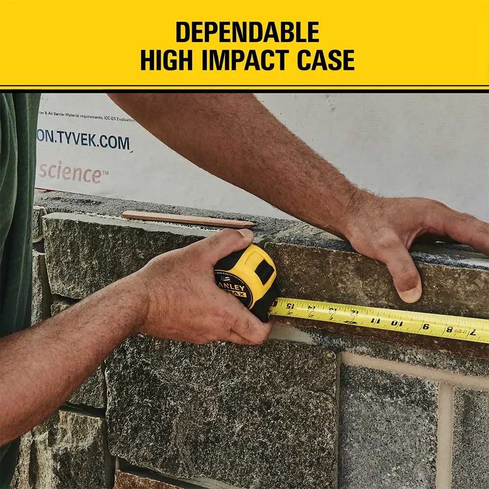 A person uses a STANLEY tape measure (SKU: 33-740) with a yellow and black high impact case to measure a stone surface. Above, the text reads 'Dependable High Impact Case.'