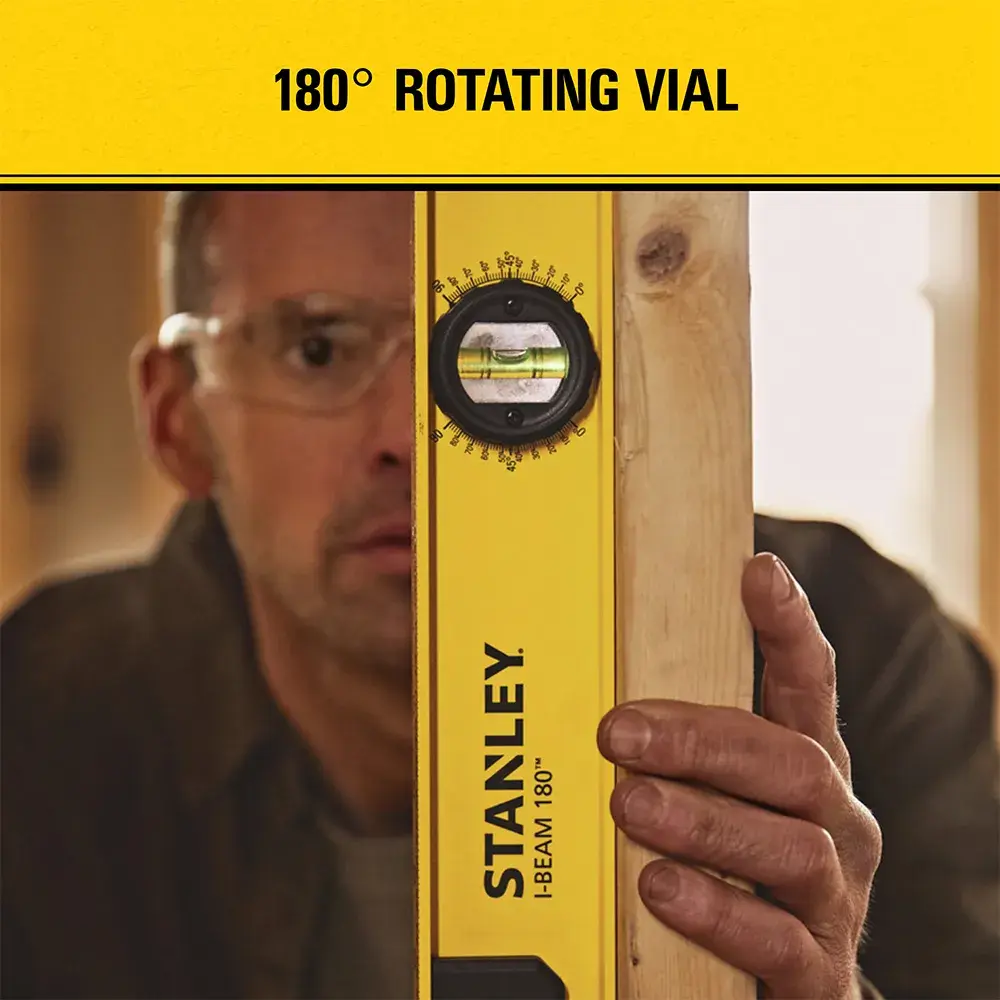 A person holds a wooden beam and a yellow Stanley 180-degree rotating vial level tool, with product features highlighted on a yellow banner at the top.
