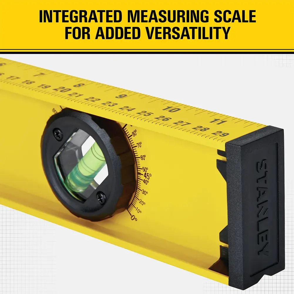 Close-up view of a Stanley brand yellow spirit level with an integrated measuring scale and a black end cap. The product features a measurement ruler and a bubble vial, and text above reads 'Integrated measuring scale for added versatility.'