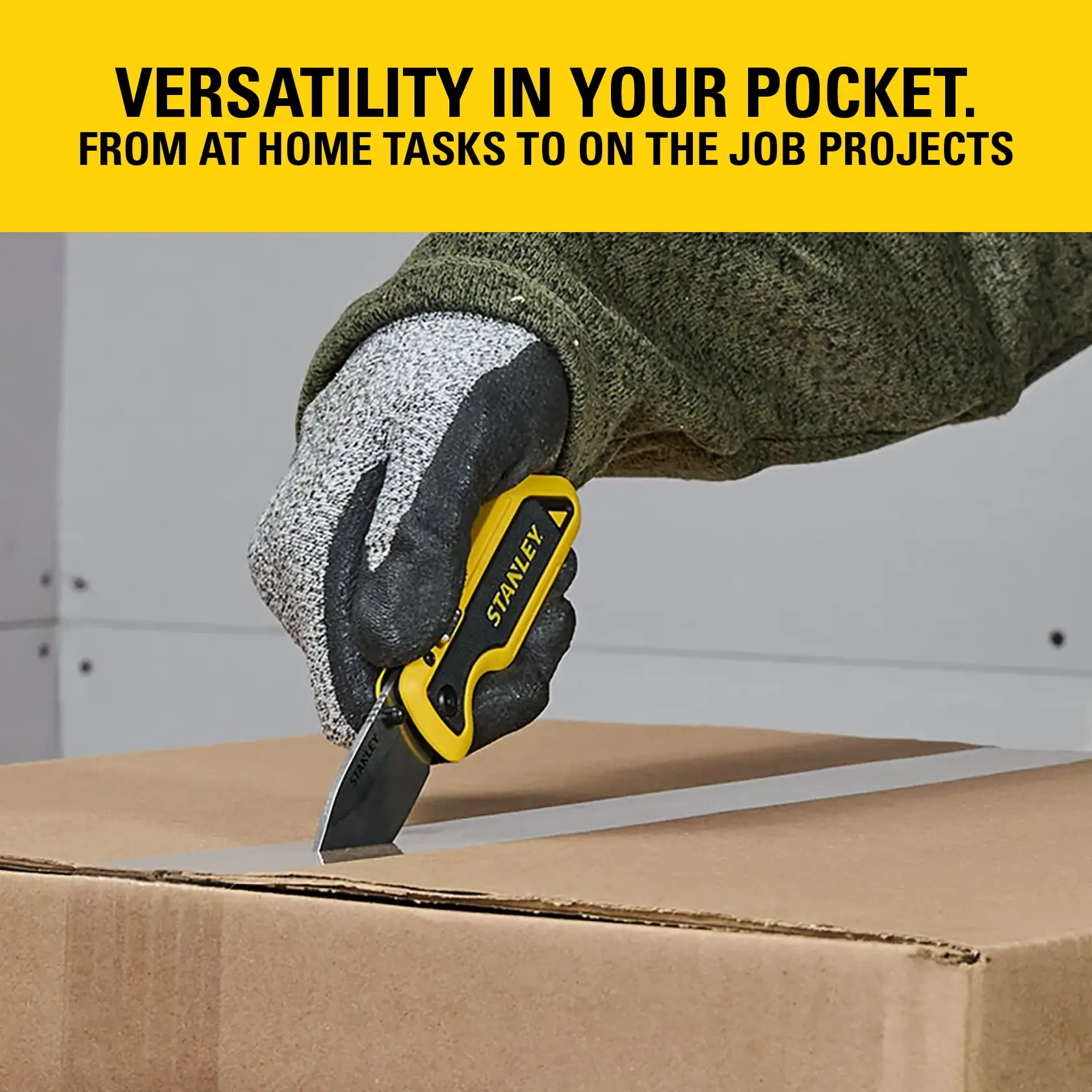 Gloved hand uses STANLEY folding utility knife to cut tape on a cardboard box; yellow and black tool shown.