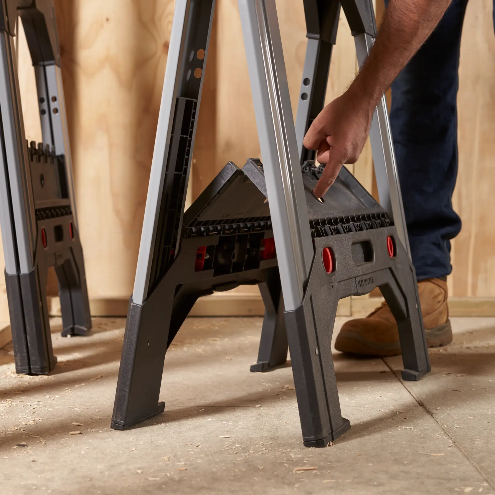 STANLEY 011031S folding sawhorse, black and gray, side angle, hand adjusting latch, workshop setting