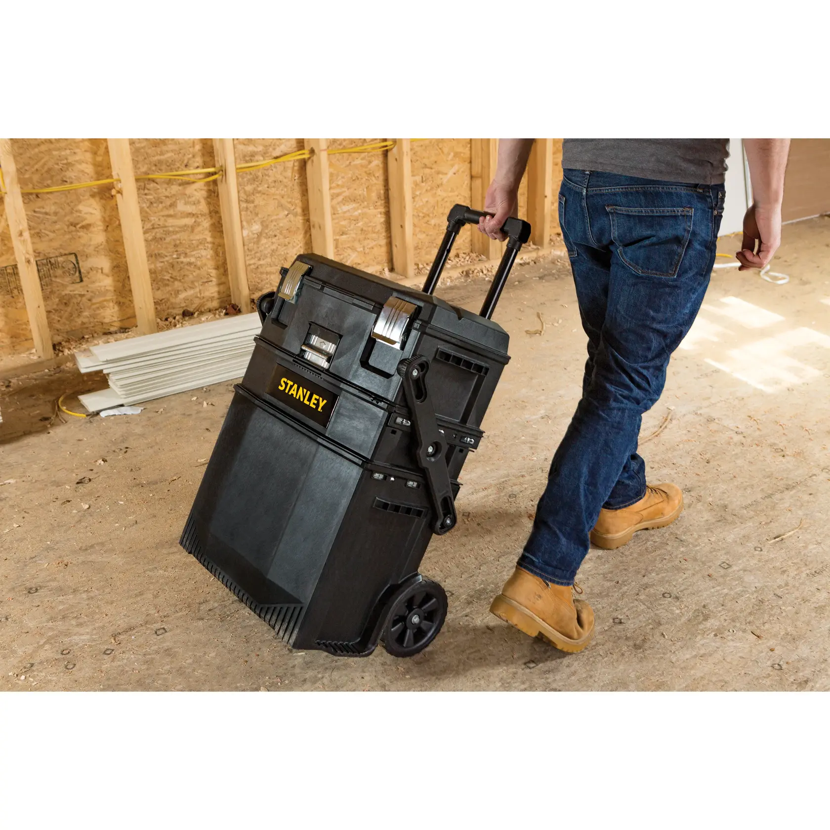 STANLEY SKU 020800R rolling tool box with handle, black, in construction site, side view.