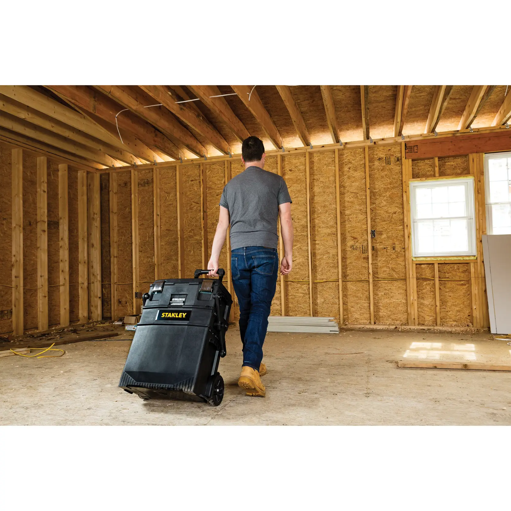 Photo of person pulling STANLEY 020800R mobile toolbox through unfinished room at construction site.
