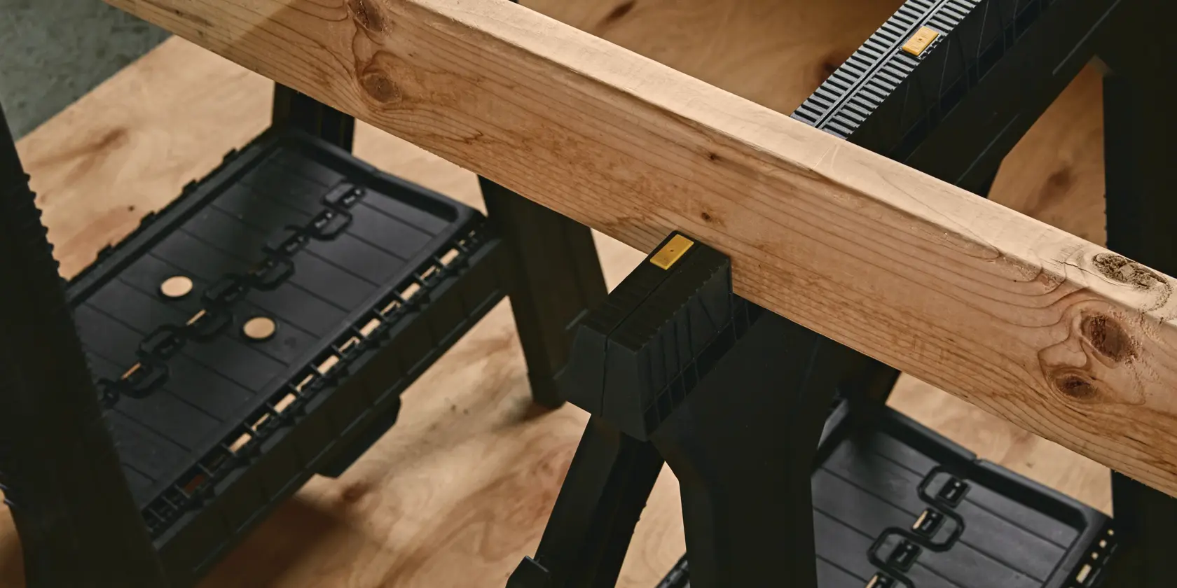 STANLEY 060864R black plastic sawhorse with wooden beam, close-up photography.