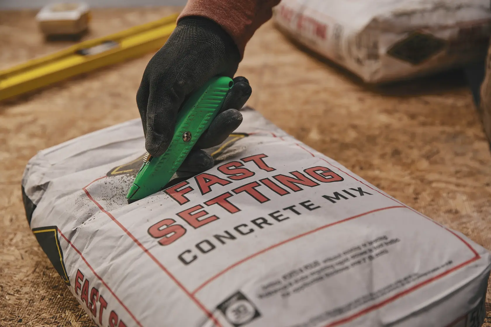 STANLEY 10-179 utility knife cutting open concrete mix bag, close-up photography.