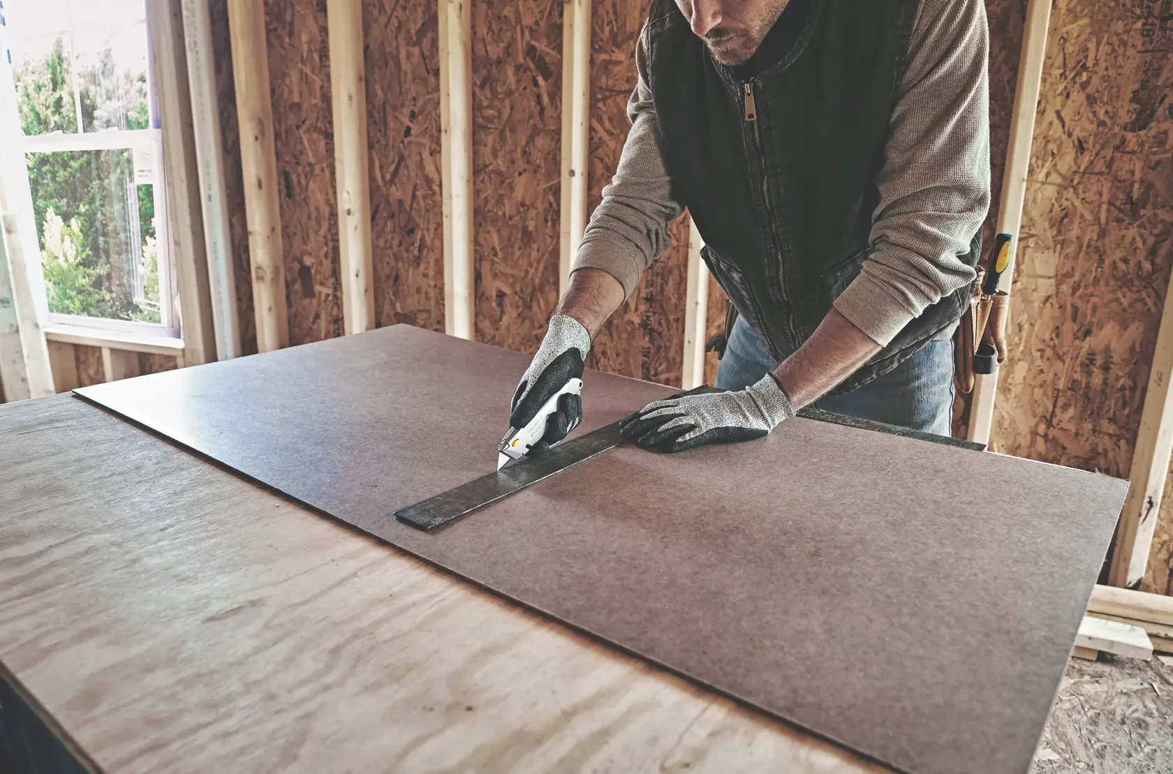 STANLEY 10-499 utility knife cutting board material along metal ruler, construction site setting.