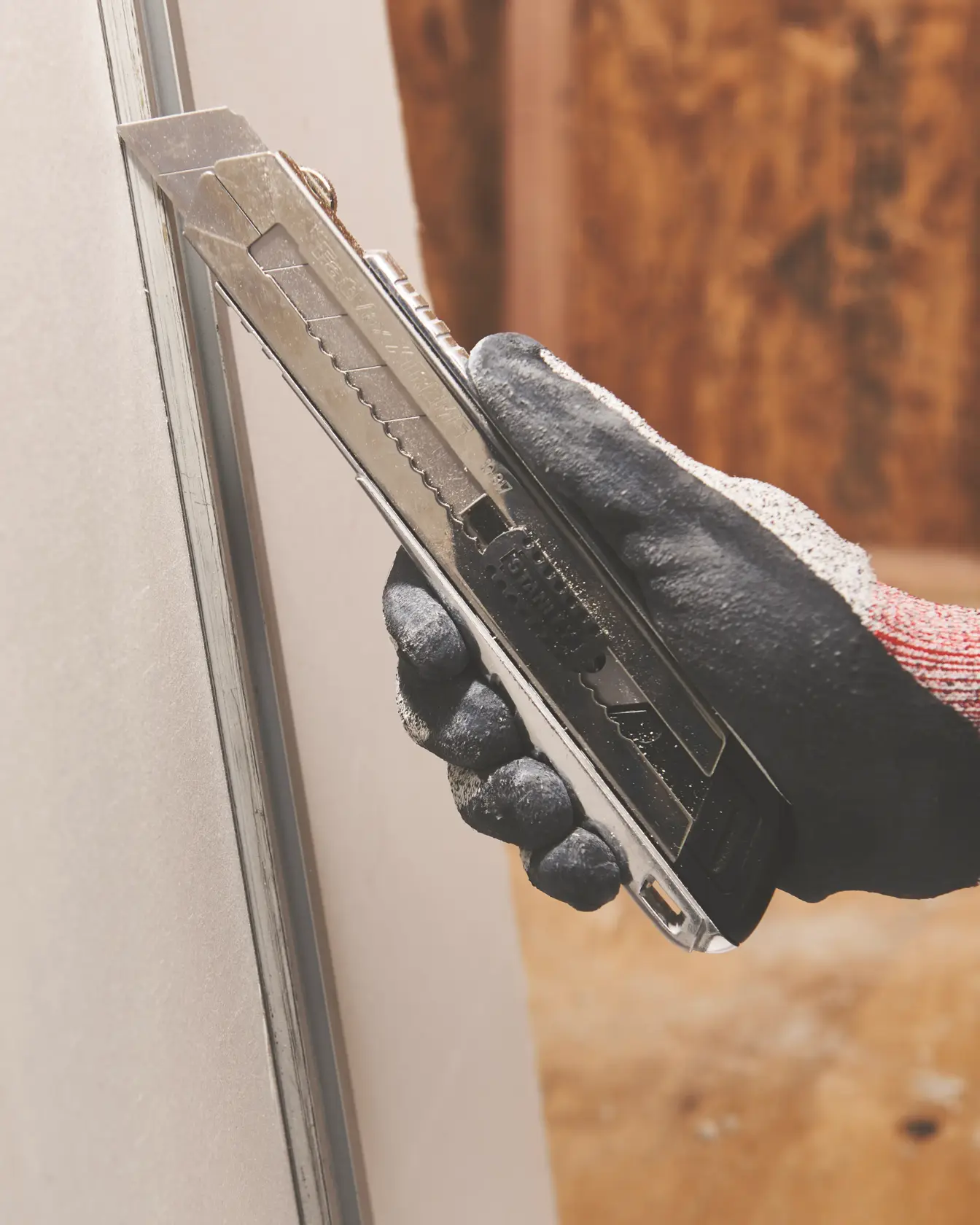 STANLEY 10-817 utility knife in use cutting drywall, close-up side angle.