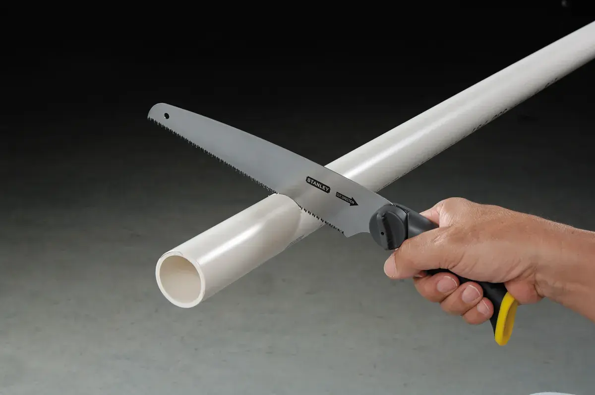Photo of STANLEY 20-092 hand saw cutting a white PVC pipe, close-up, with black and yellow handle visible.