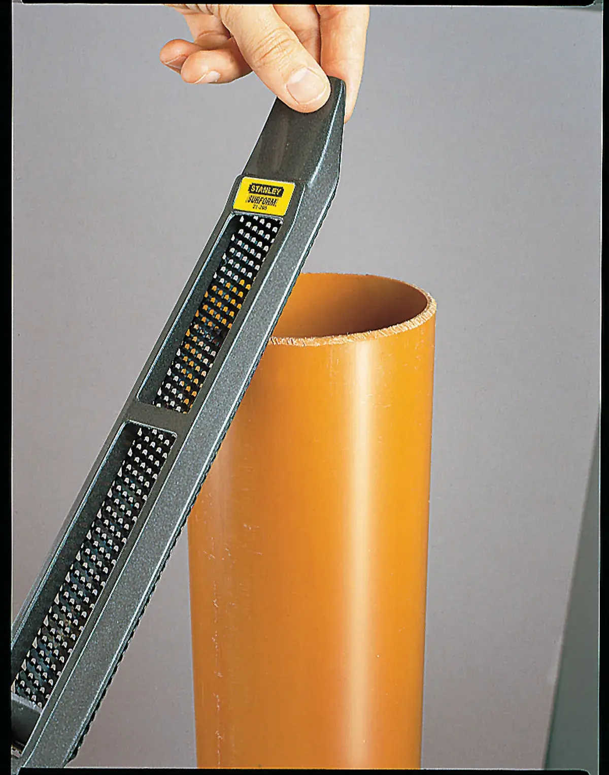 Photo of STANLEY 21-295 hand rasp being used to smooth the edge of an orange plastic pipe.