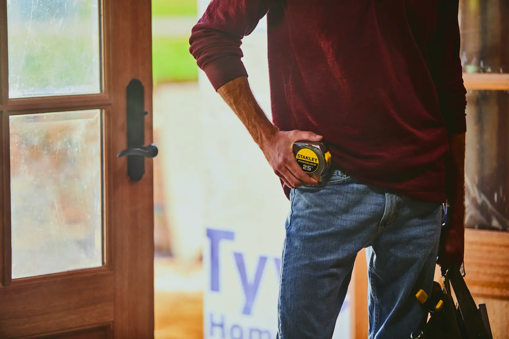 STANLEY 33-425 tape measure held by person wearing jeans, partial indoor setting, photography