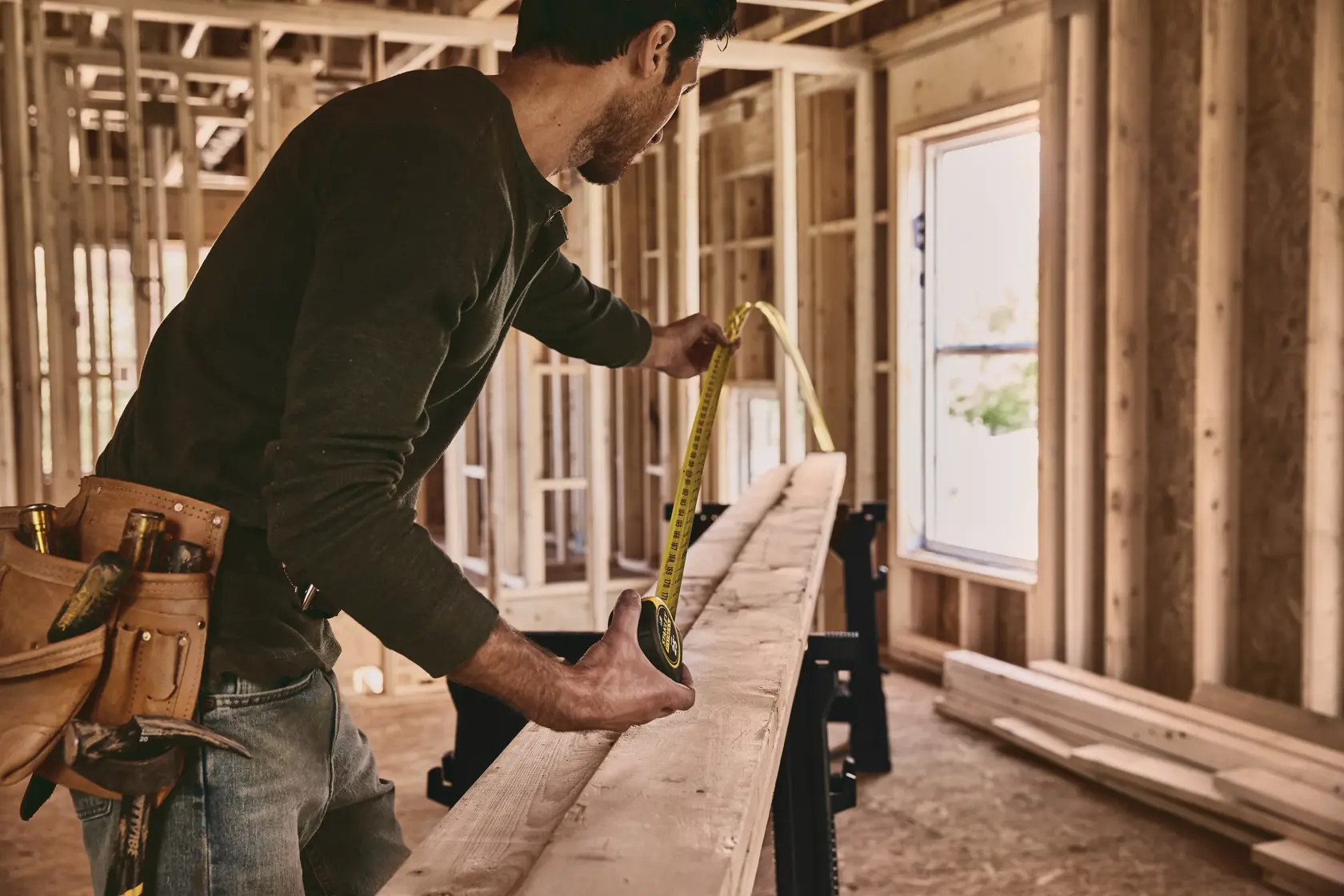 STANLEY 33-725 tape measure used to measure wooden plank in construction site, side angle photography.