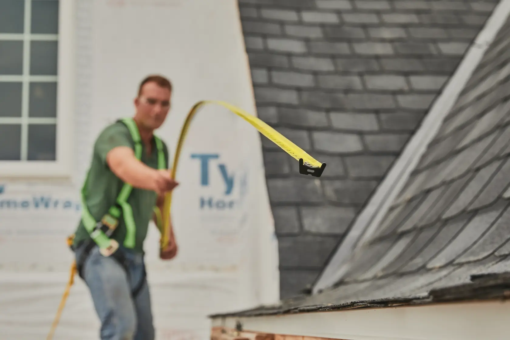 STANLEY 33-735 tape measure photography showing a worker extending yellow tape on a residential rooftop.