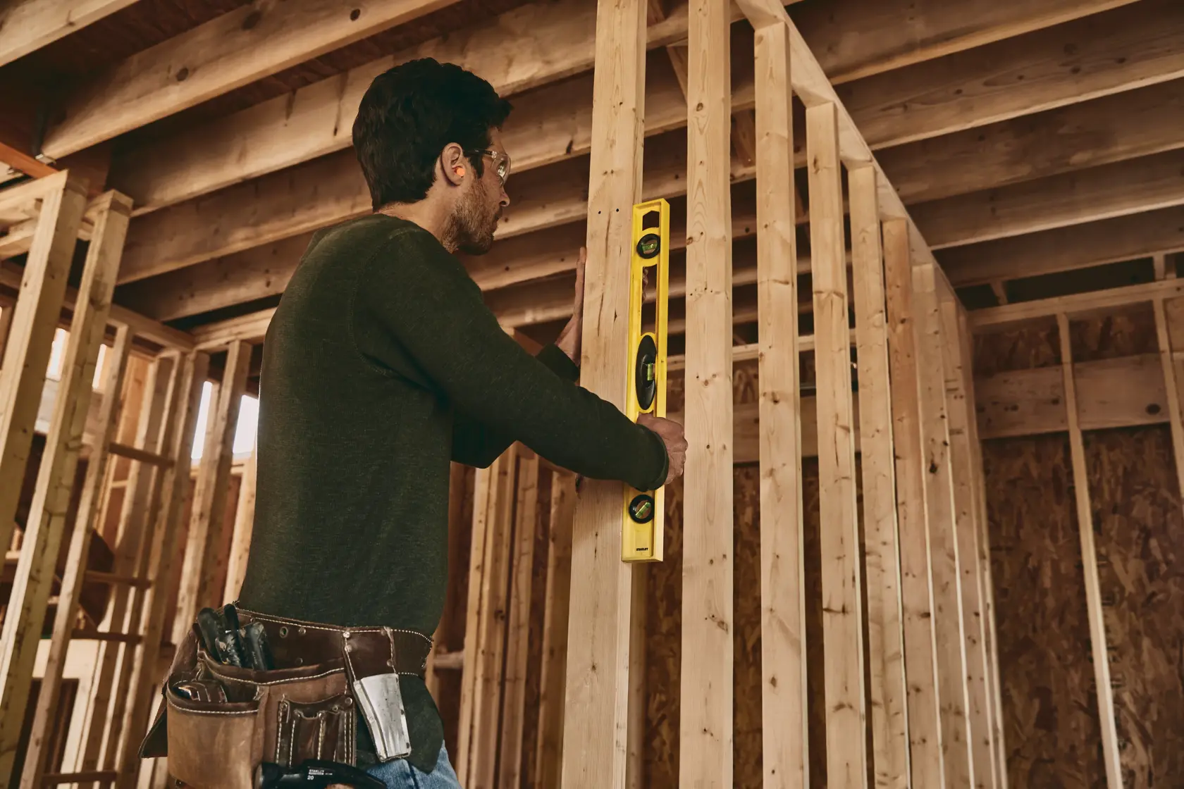 STANLEY 42-468 level tool used by worker in unfinished wood frame structure, side angle photo.
