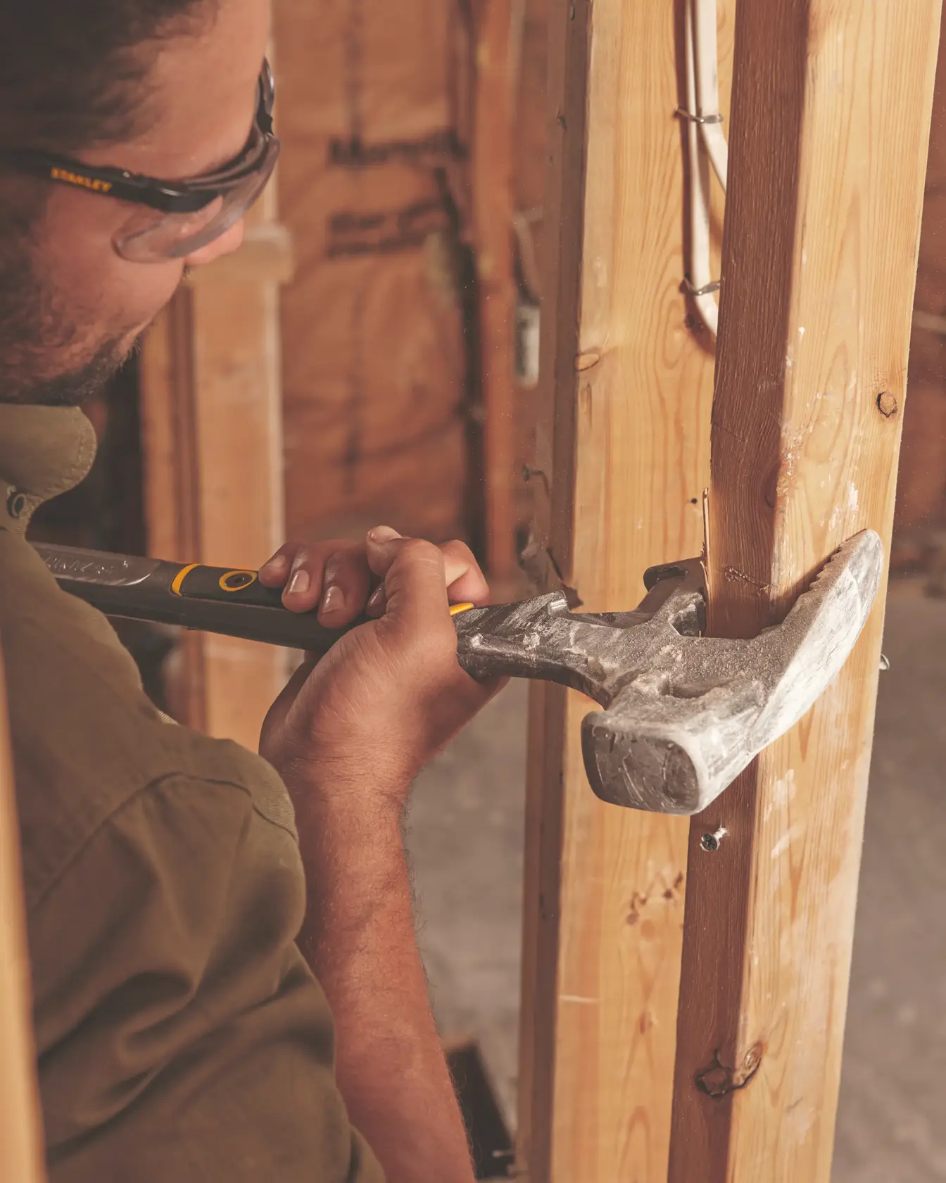 STANLEY 55-120 claw hammer held by person working on wooden beam, close-up photography.