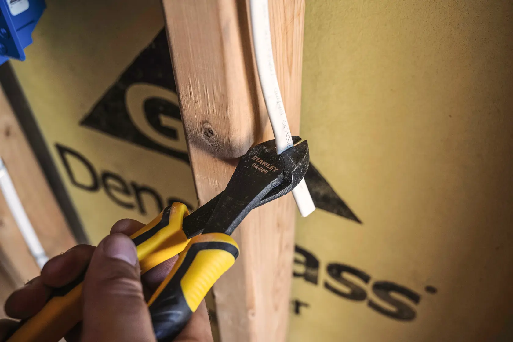 Stanley 84-028 diagonal cutting pliers cutting a white wire, close-up photo with yellow and black handles.