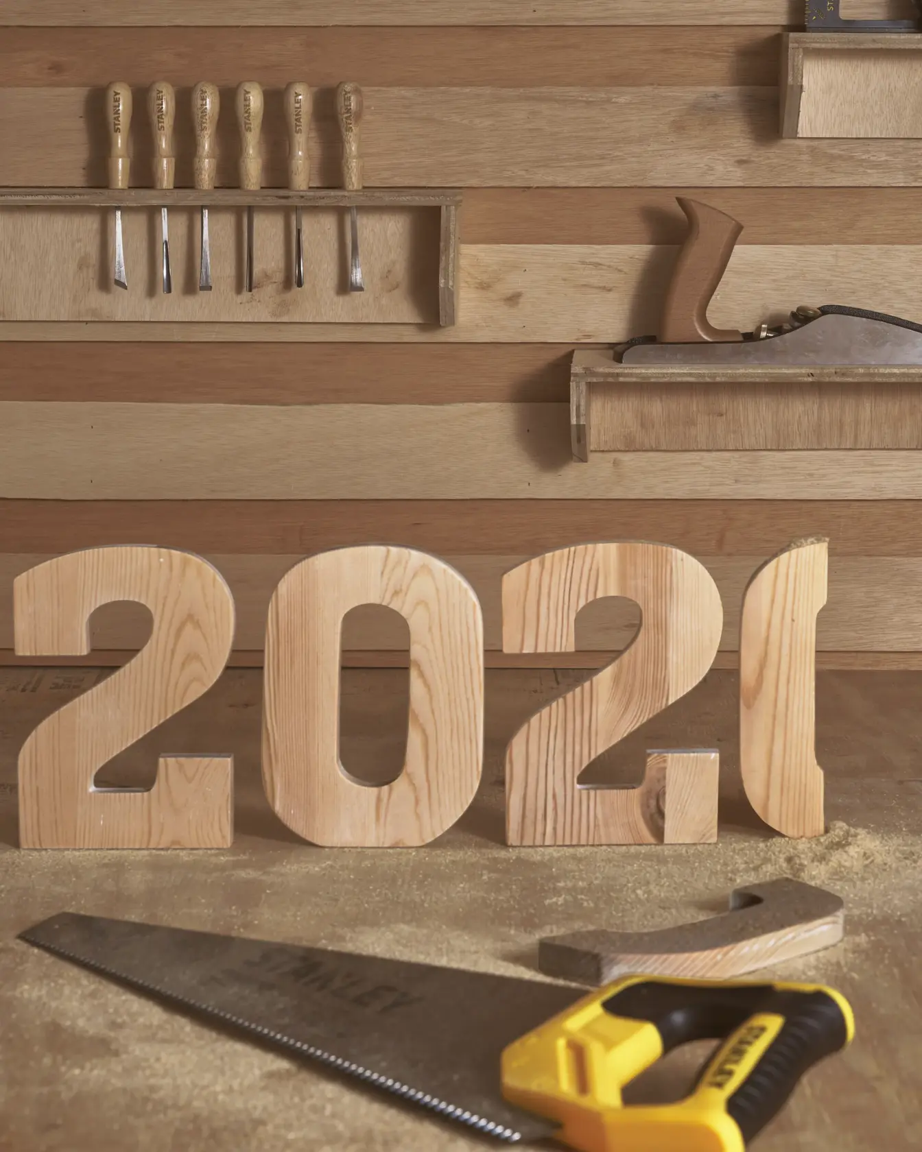STANLEY STHT20348 hand saw on workbench with wooden 2021 numbers, woodworking tools in background, front angle