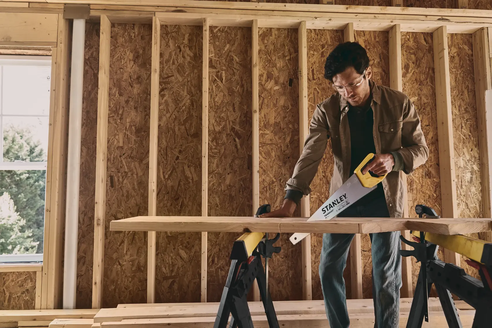 STANLEY STHT20350 hand saw in use cutting wood, photo of product in construction setting.