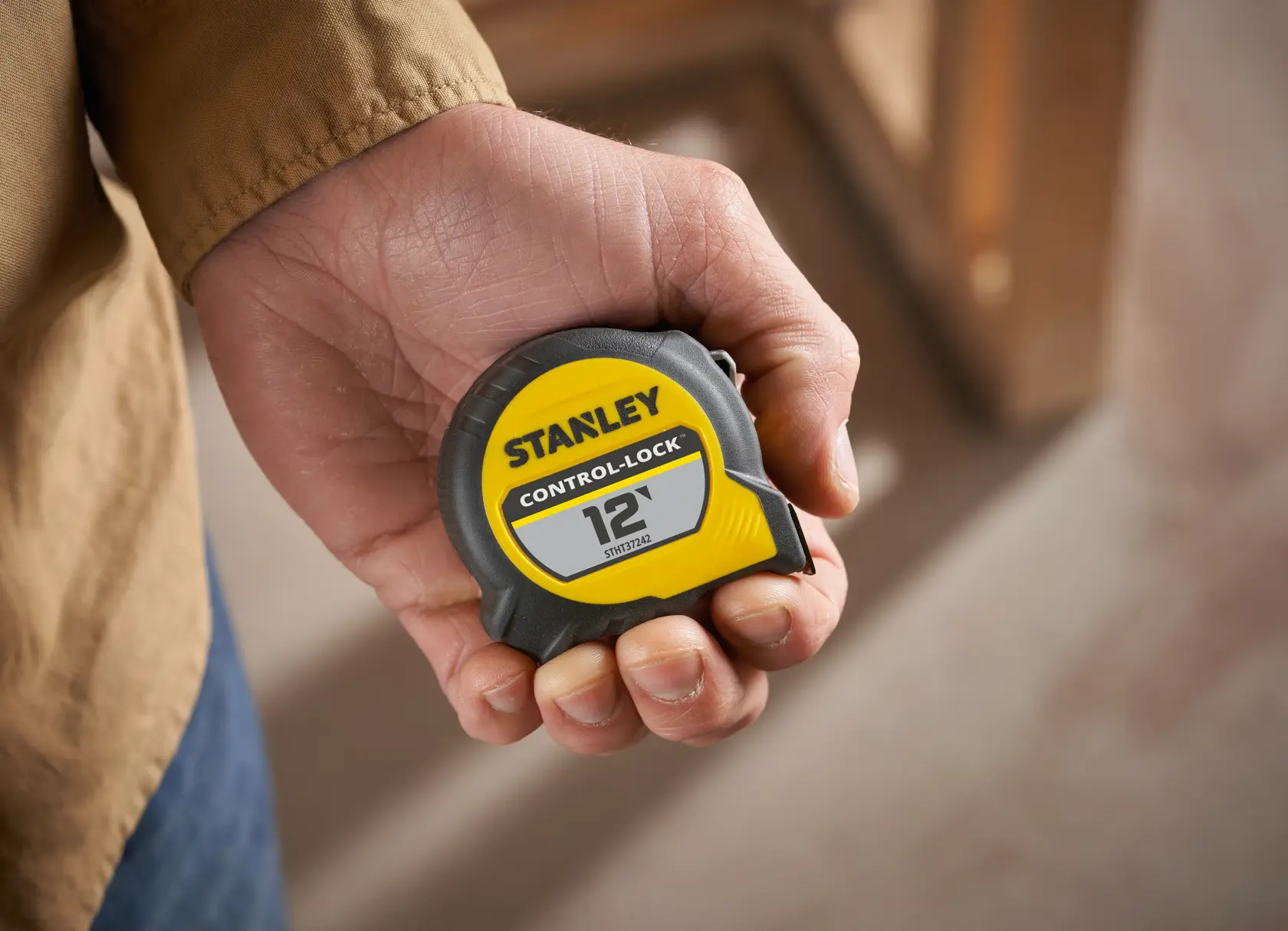 STANLEY STHT37242 yellow and black 12-foot Control-Lock tape measure held in a hand, close-up photography.