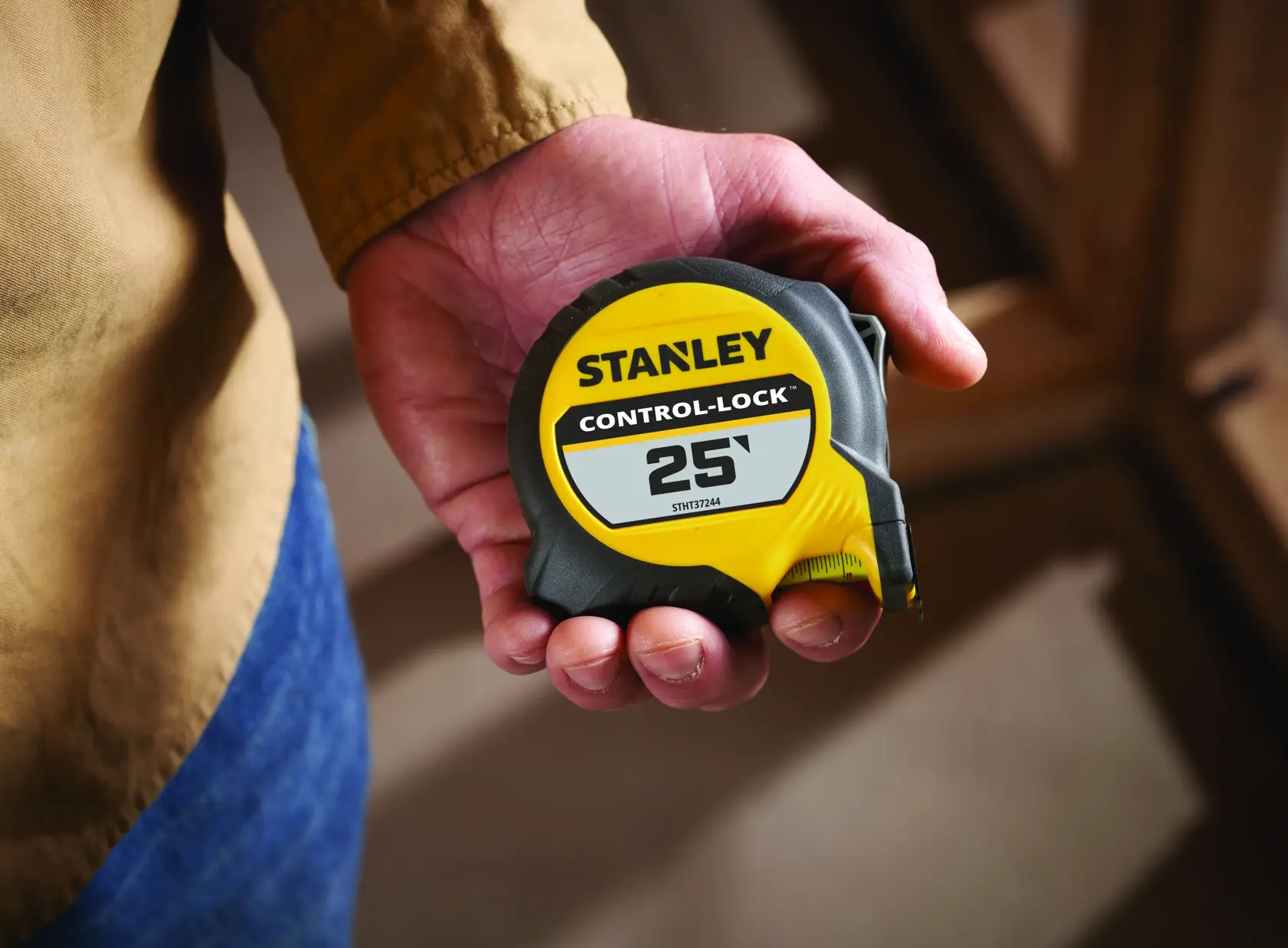 STANLEY STHT37244 25-foot Control-Lock tape measure held in a hand, yellow and black casing.