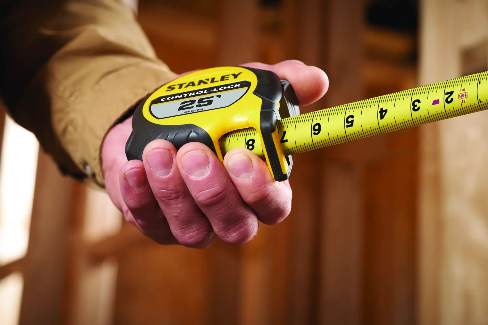 Stanley STHT37244 tape measure held in hand, yellow and black design, close-up side angle.