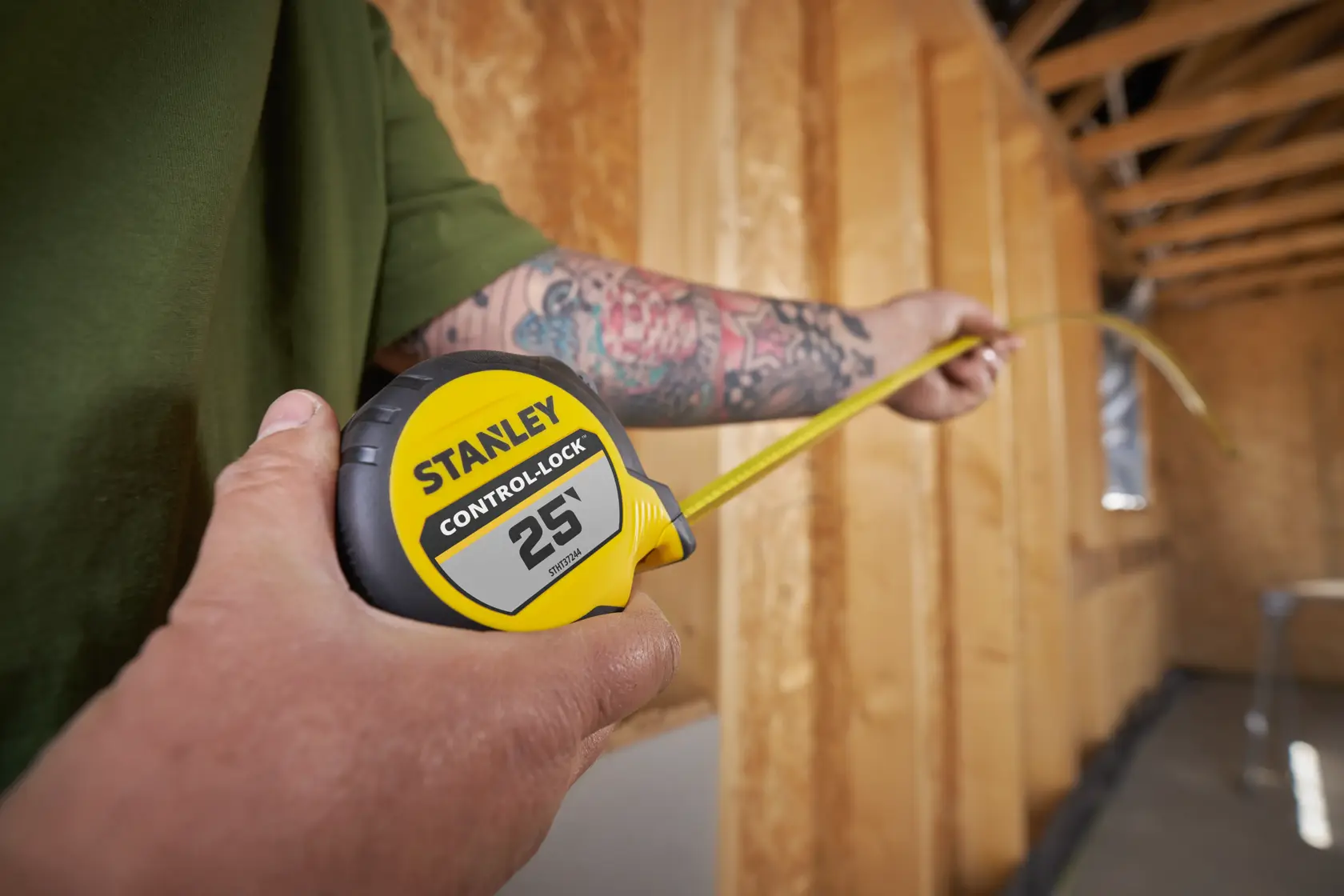 STANLEY STHT37244 tape measure with yellow casing and CONTROL LOCK 25' label in use at construction site.