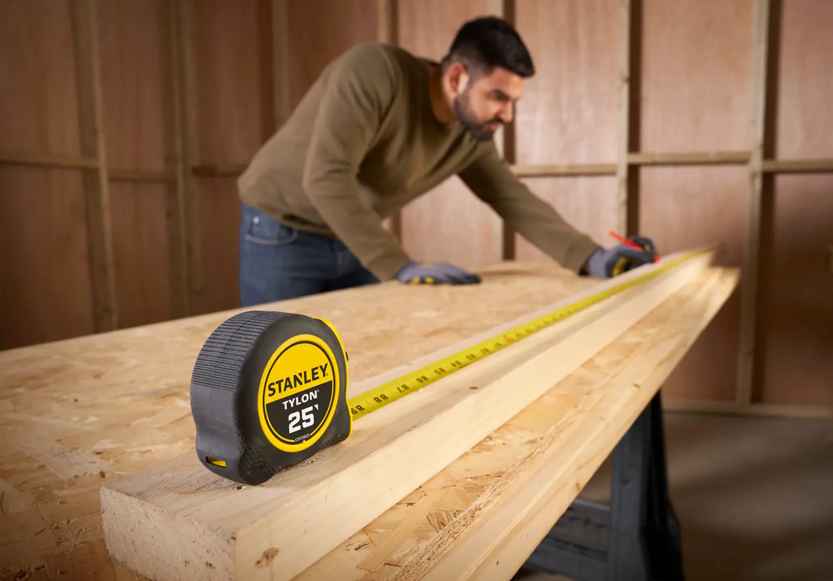 STANLEY STHT39525 tape measure in use on a wooden workbench in a workshop.