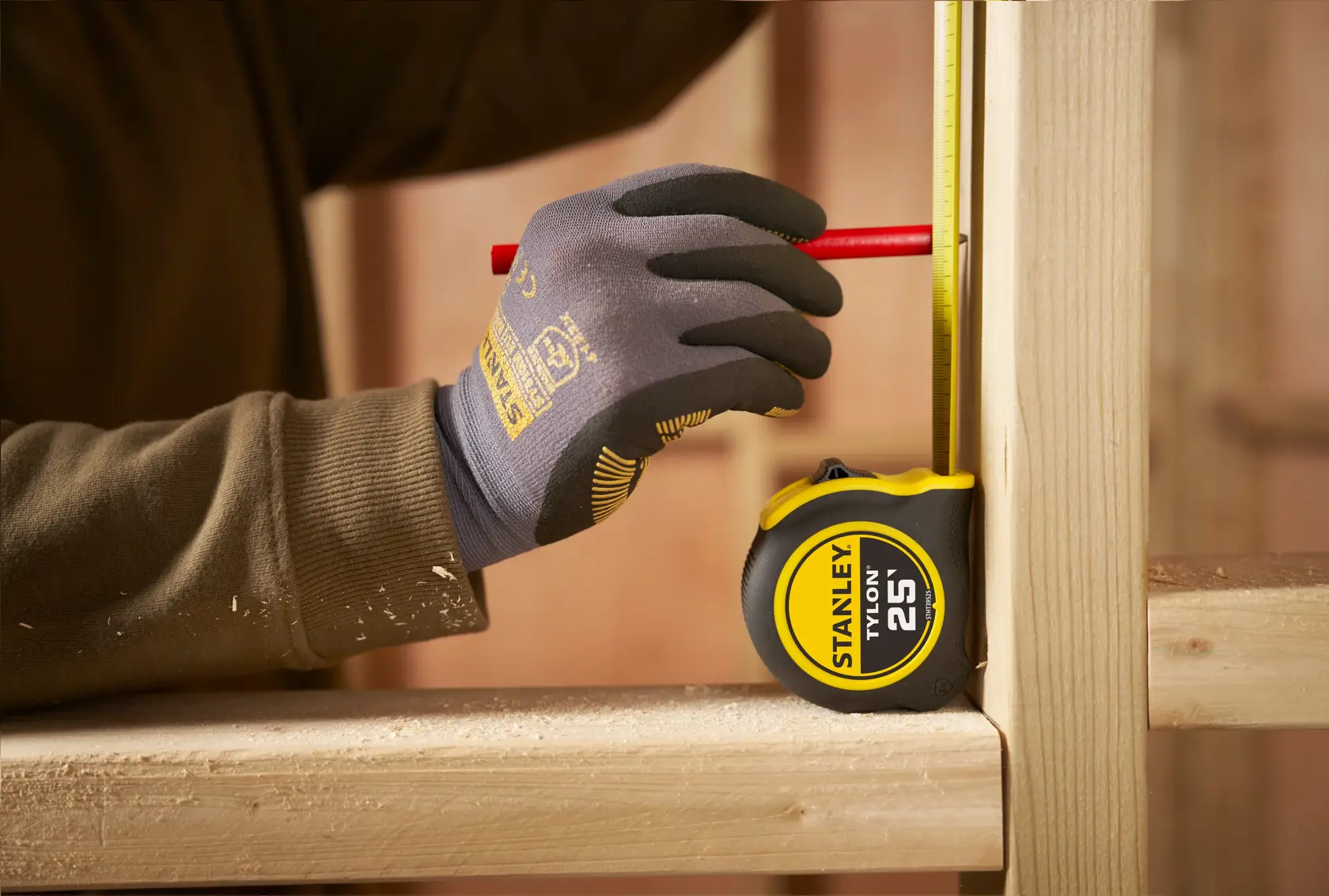 STANLEY STHT39525 tape measure with yellow and black casing in use, measuring vertical wooden beam.