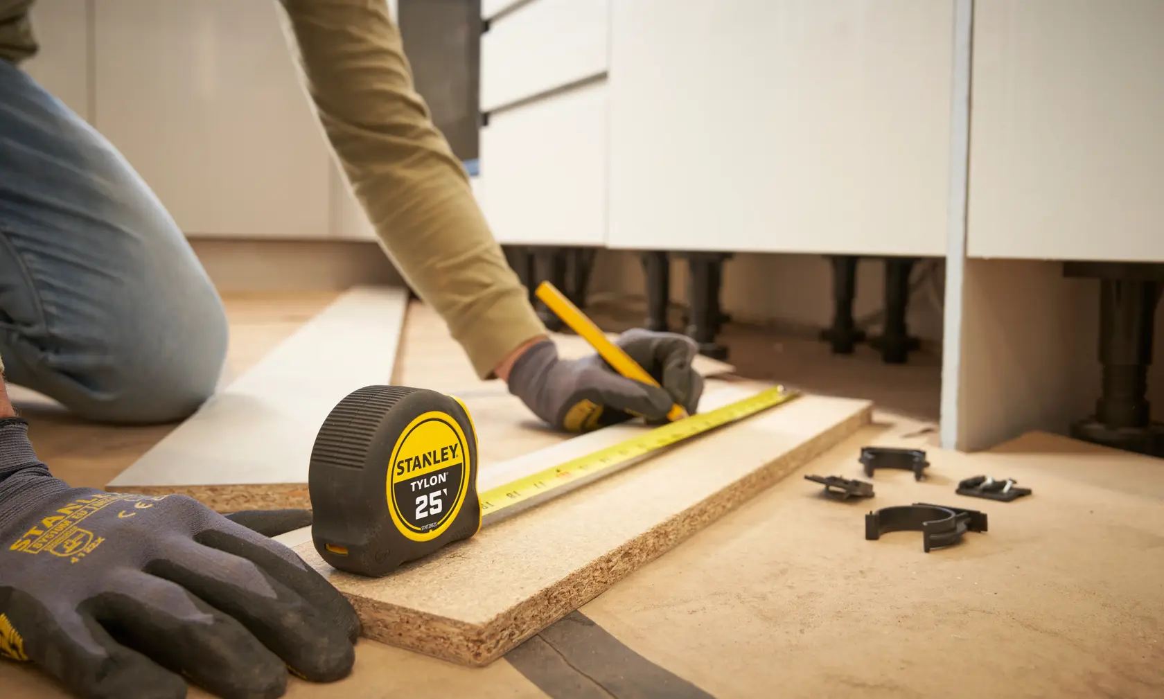 STANLEY STHT39525 tape measure on wood, person marking measurement with pencil, photography side angle.