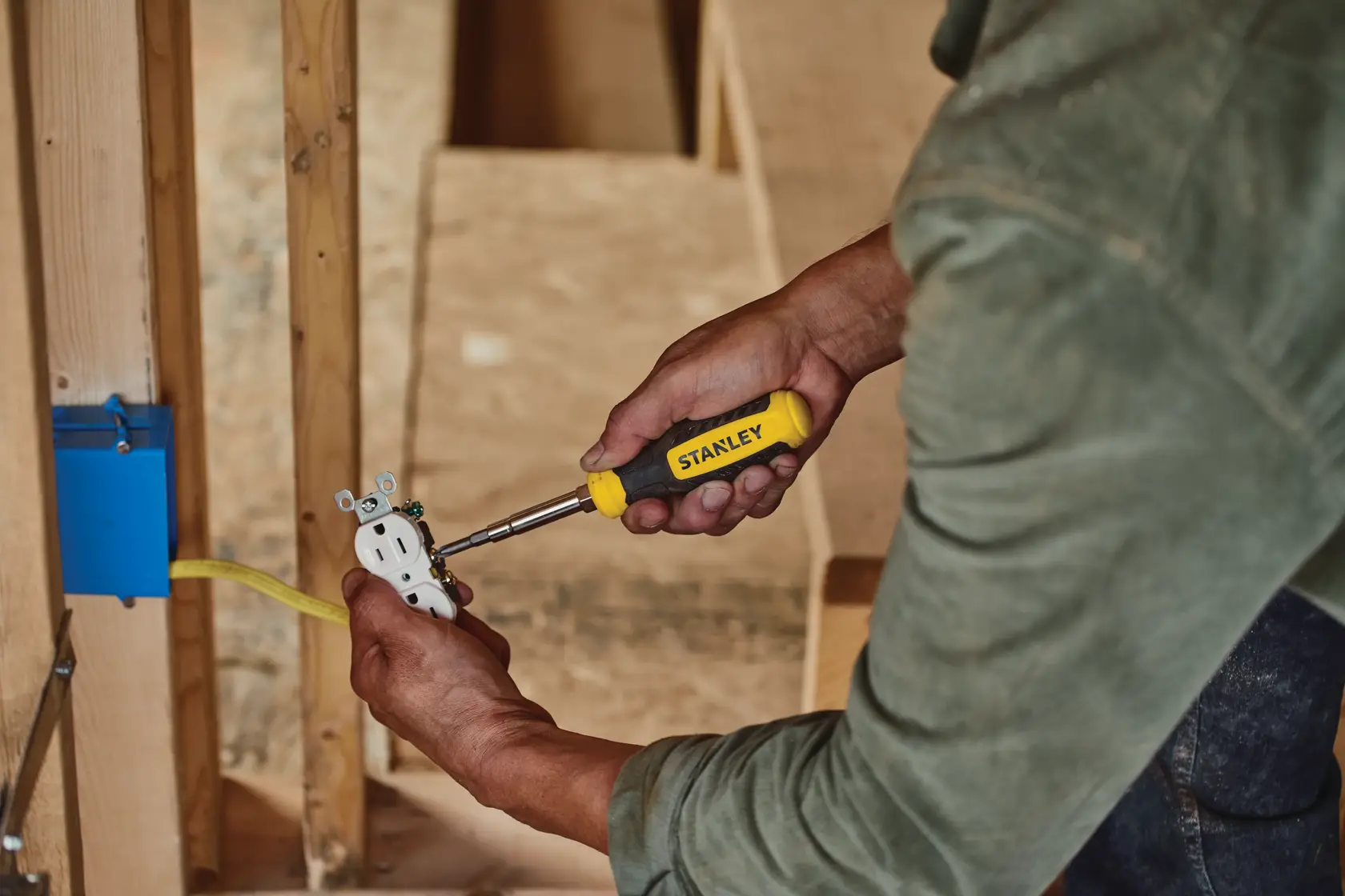 Stanley STHT60083 screwdriver held by a person wiring an outlet, close-up photography of tool in use.