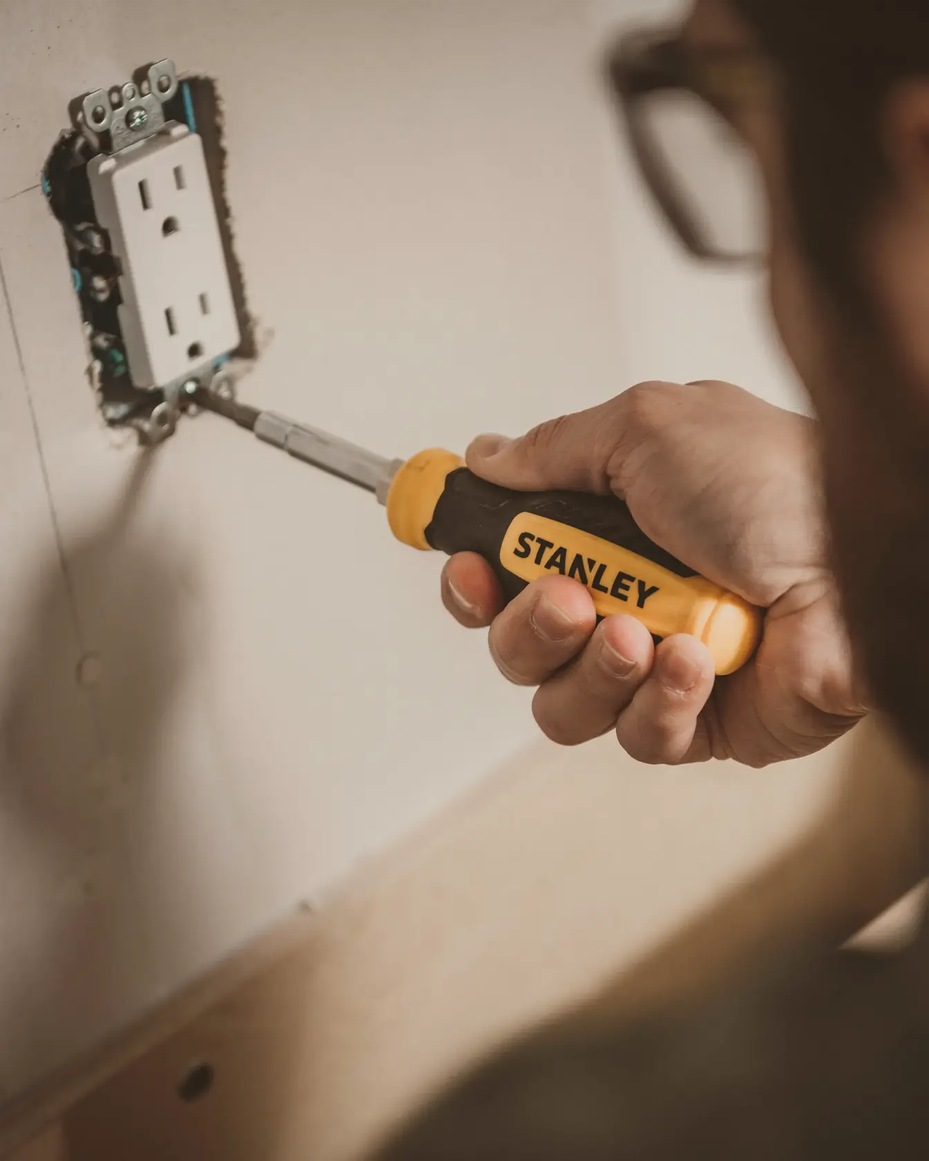 STANLEY STHT60083 screwdriver used to install wall outlet, close-up view, yellow and black handle.
