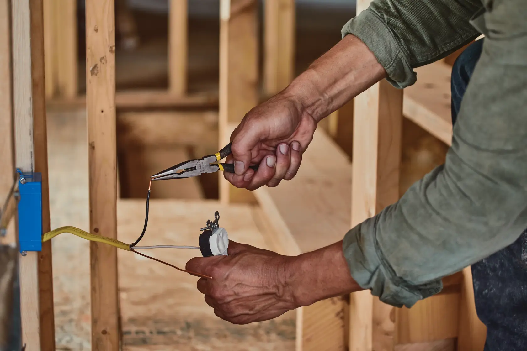 STANLEY STHT84402 long nose pliers used to grip wire during electrical installation in construction setting.