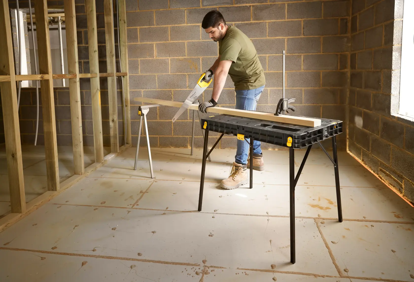 Photo of STANLEY STST11552 workbench in use with wood plank and saw in a construction setting.