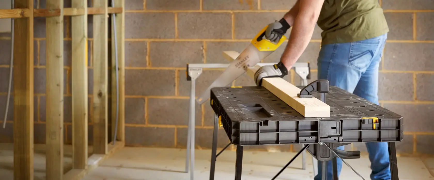 STANLEY STST11552 workbench in use, black folding table holding wood plank in workshop setting.