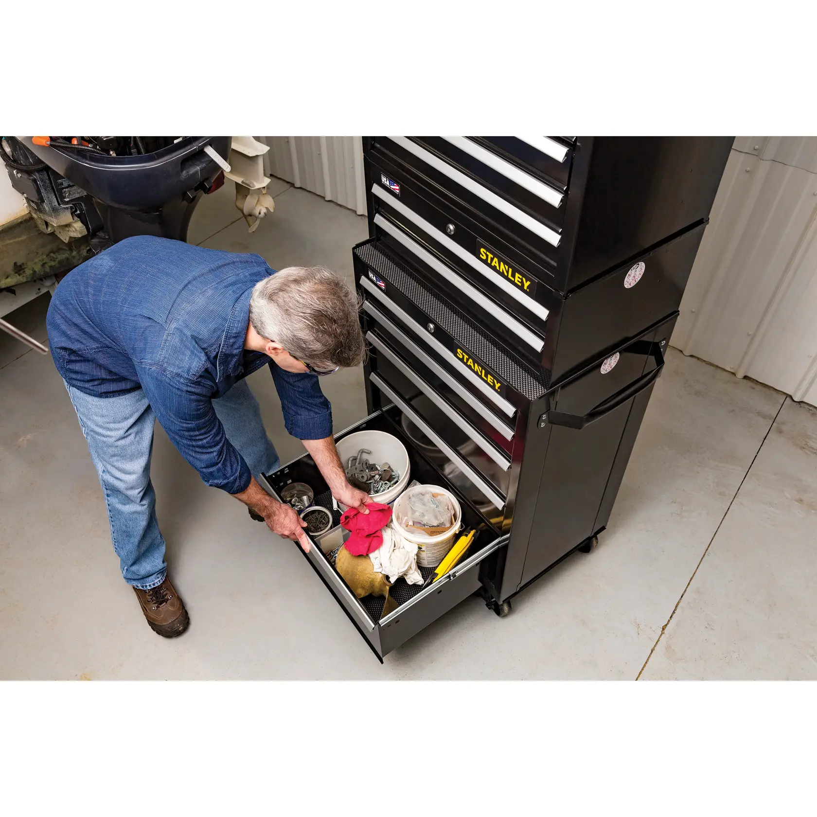 Photo of STANLEY STST22657BK tool chest with open bottom drawer, man organizing tools and supplies in a garage.