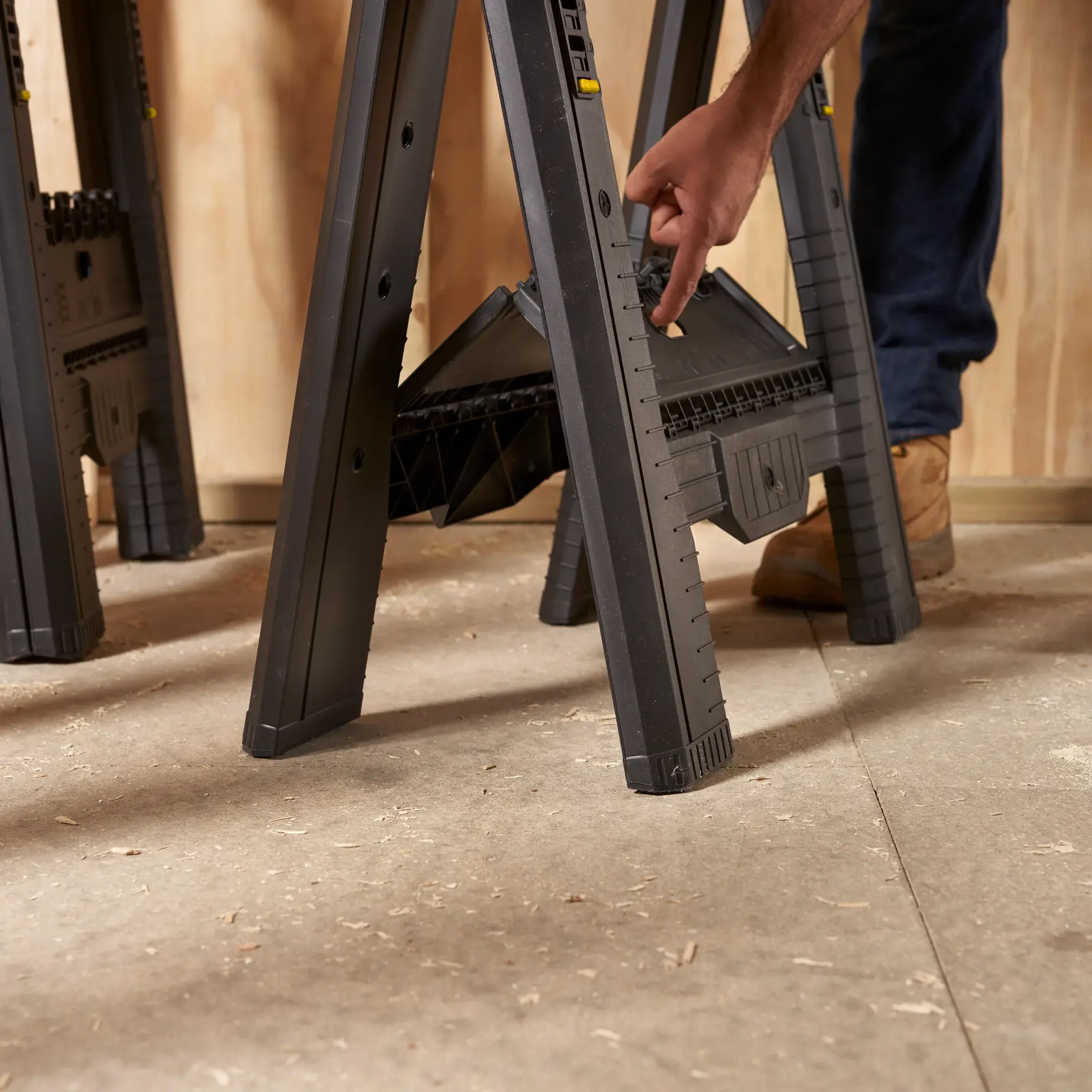 STANLEY STST60626 plastic sawhorse, side angle, adjustable leg feature in workshop setting.