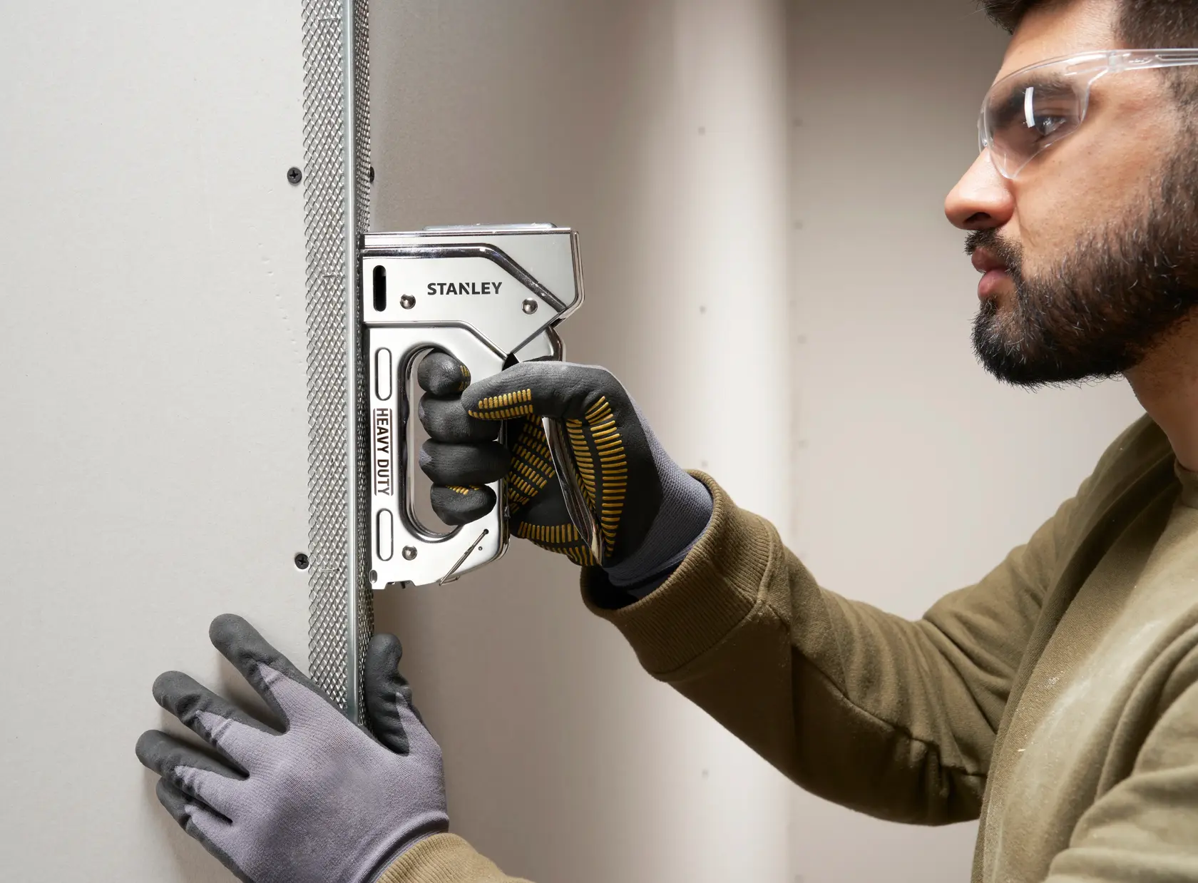 Stanley TR110 heavy duty staple gun in use attaching metal corner bead to drywall.