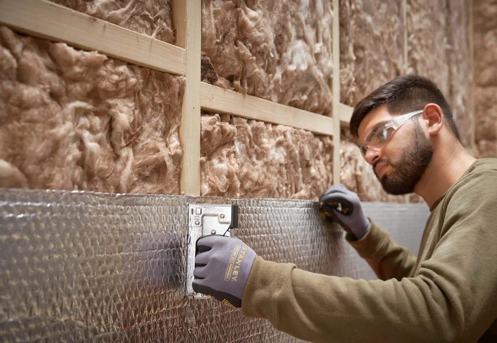 Stanley TR45 staple gun used to secure insulation with foil backing, side view in construction setting.